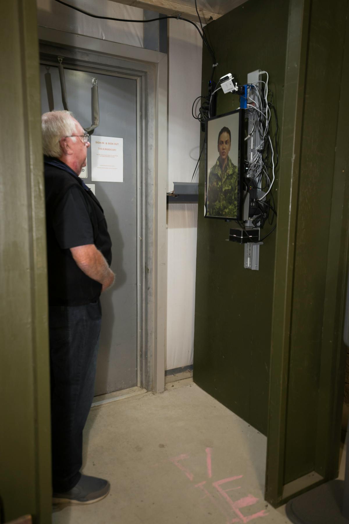 Figure 2: A volunteer from the Ontario Regiment Museum stands in a vestibule for COVID-19 screening questions delivered by the Master Cpl. Lana AI assistant, followed by a temperature check with a FLIR thermal imaging module.