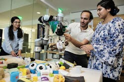 MIT researchers demonstrate FuseBot, a robotic arm and gripper, as it retrieves a hidden item from a pile. Pictured are Research Assistant Tara Boroushaki, Associate Professor Fadel Abid, and Research Assistant Nazish Naeem. (Photo courtesy of MIT.) MIT researchers demonstrate FuseBot, a robotic arm and gripper, as it retrieves a hidden item from a pile. Pictured are Research Assistant Tara Boroushaki, Associate Professor Fadel Abid, and Research Assistant Nazish Naeem. (Photo courtesy of MIT.)
