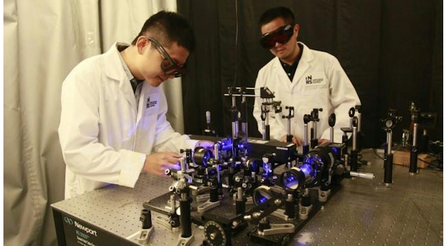 Researchers Xianglei Liu and Jinyang Liang working on the optical setup for their ultra high speed mapping camera.