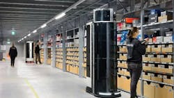 Robots and humans working side by side. The robots are picking the top shelves, which are harder to reach and ergonomically taxing for human workers.