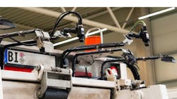 Cameras are mounted on movable arms at the top of a waste disposal truck, just above the truck's pour chamber. These cameras will take images of the inside of a customer's waste disposal bin before it is dumped into the truck. Cameras are mounted on movable arms at the top of a waste disposal truck, just above the truck's pour chamber. These cameras will take images of the inside of a customer's waste disposal bin before it is dumped into the truck.